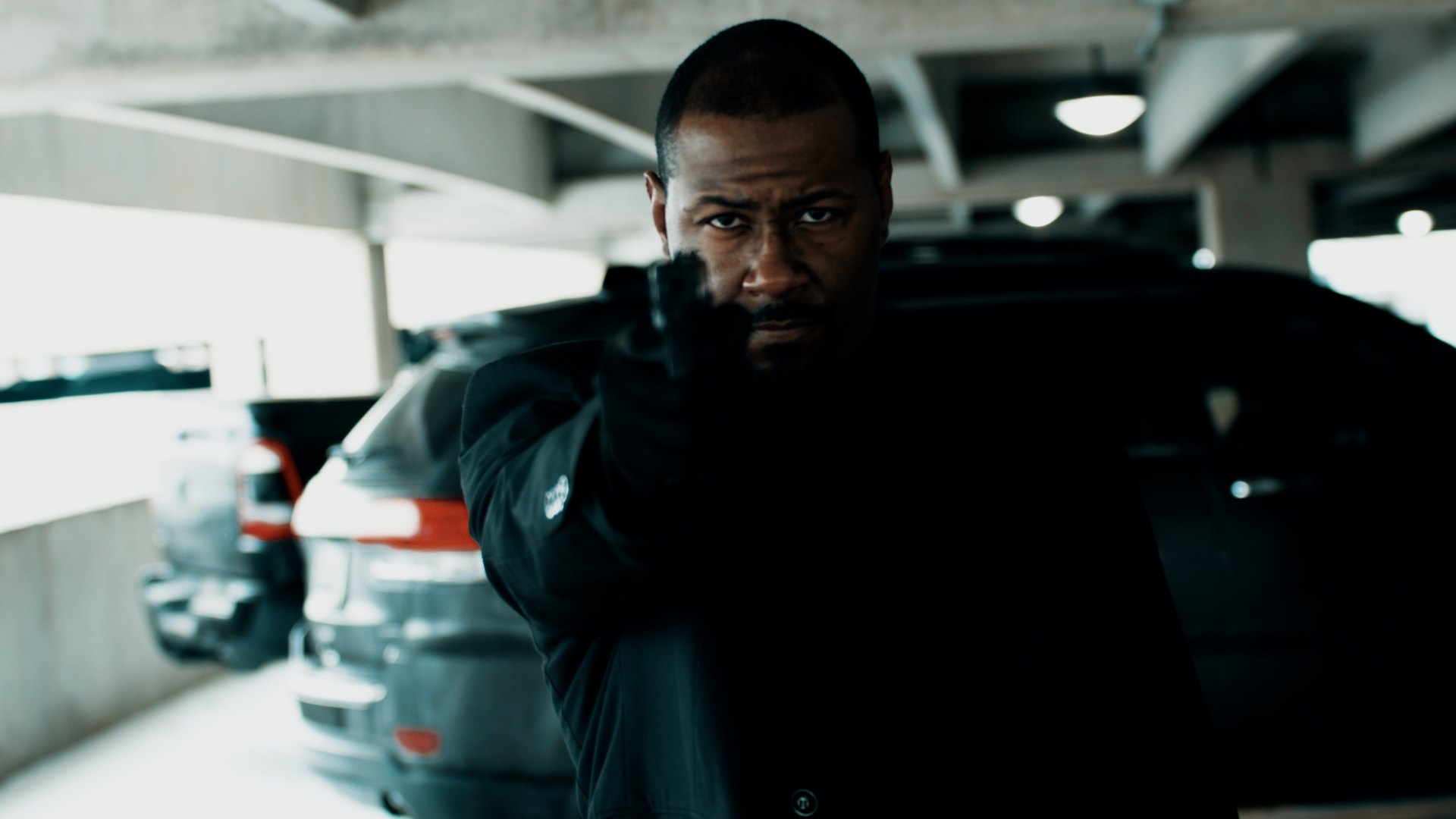 Man aiming a prop firearm in a garage film scene